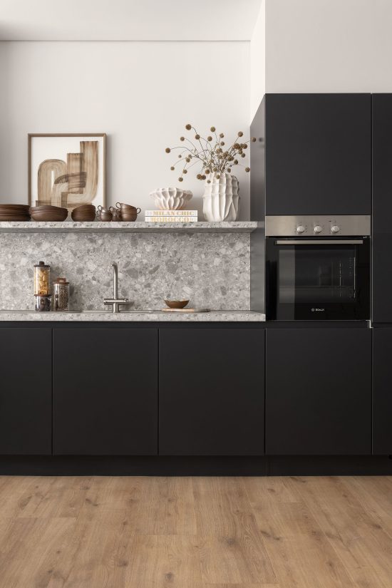 Modern apartment kitchen at White City Limassol Aparthotel, featuring sleek black cabinetry, marble countertops, and bar stools for casual dining.